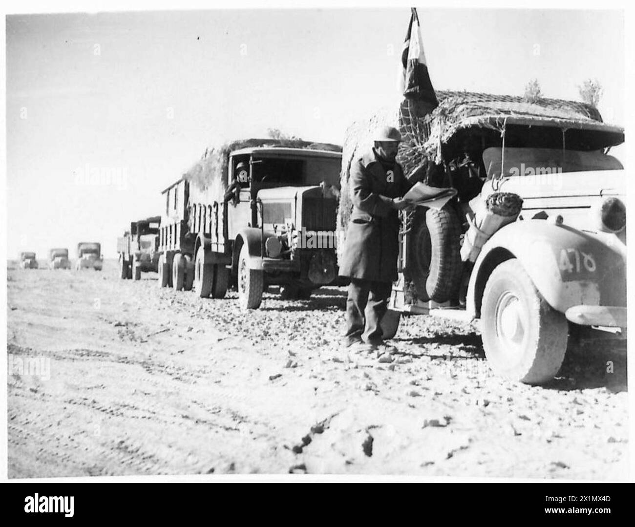 Gefangene Fahrzeuge, eines mit italienischer Flagge, bewegen sich während der Operationen der britischen Armee in Nordafrika und im Nahen Osten, 1940–1947, auf eine Basis zu. Stockfoto