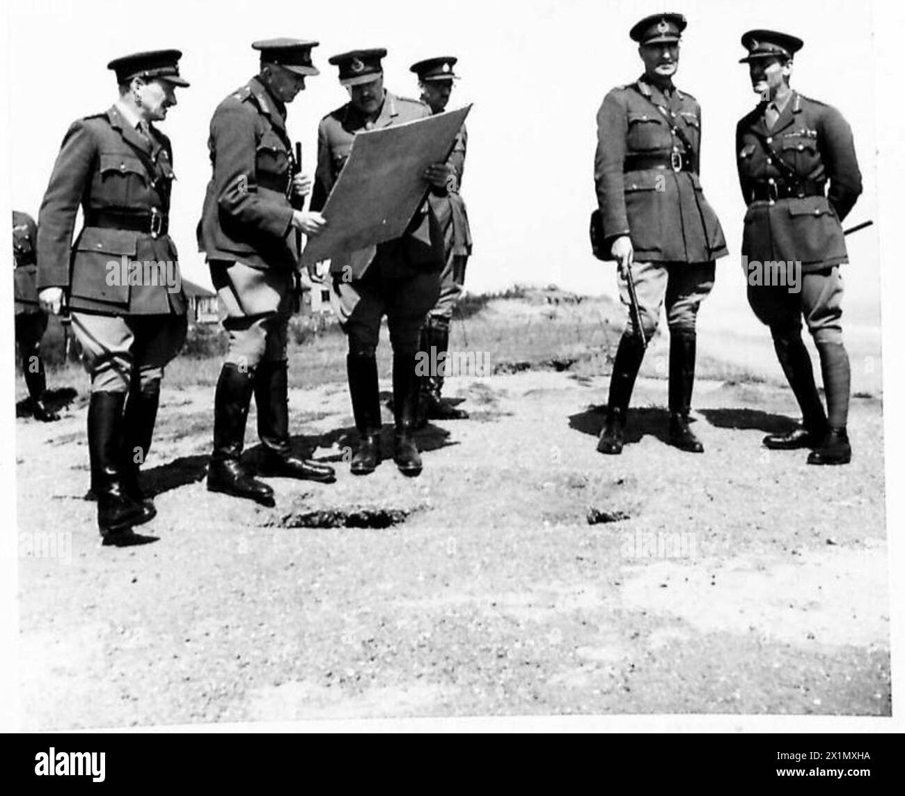 Hochrangige Offiziere der britischen Armee, einschließlich des Oberbefehlshabers, besuchen Küstenverteidigungen und studieren eine Karte auf Klippen, um strategische Positionen zu bewerten. Stockfoto