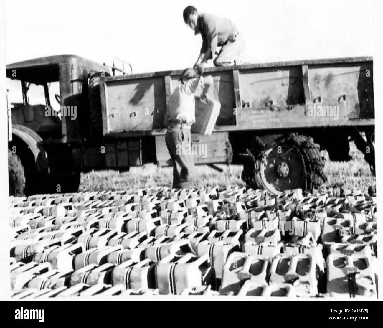 Die Corporals J. Johnson und G.A. Yates der 3231 S.C.U. kümmern sich um Benzinkanister aus einem 3-Tonnen-LKW während des Baus eines Landeplatzes in Italien für die britische Armee. Stockfoto