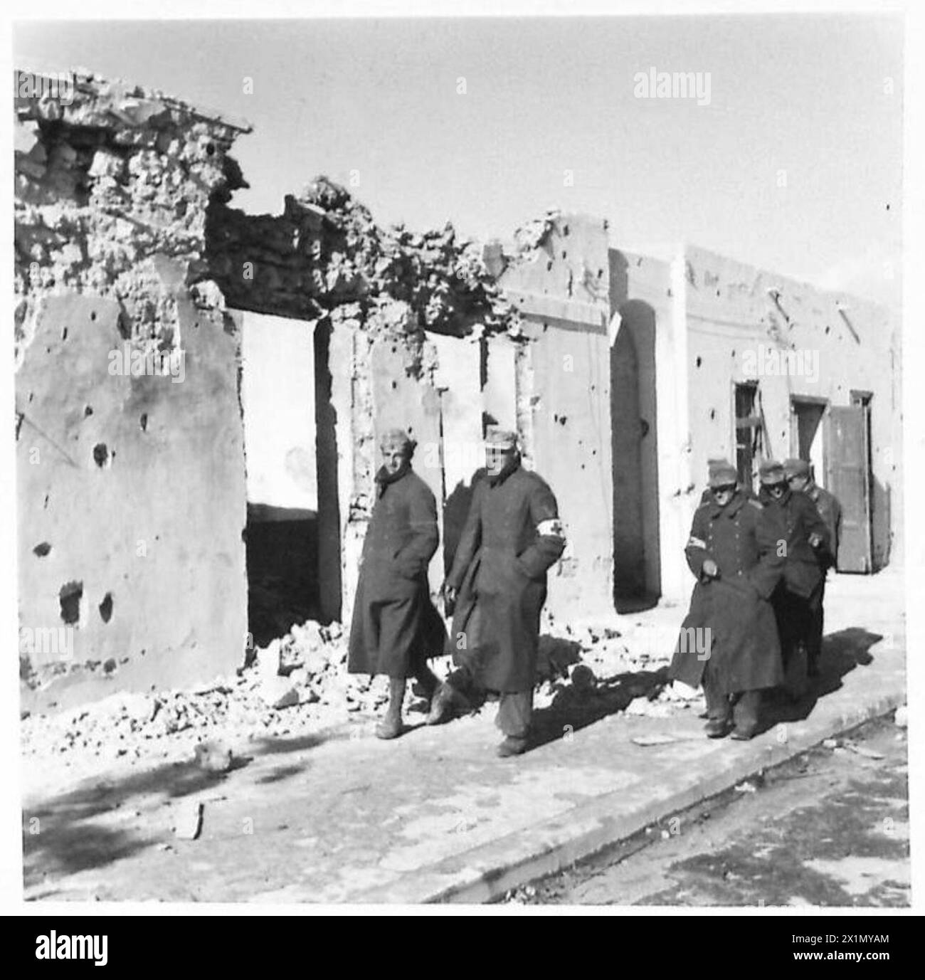 Deutsche und italienische Gefangene, von denen viele Rote Kreuze tragen, passieren Bardia auf dem Weg zu einem Gefangenenlager während der Operationen der britischen Armee. Stockfoto