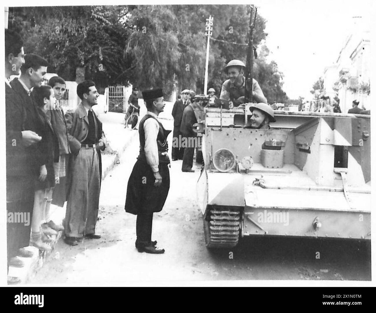 Britische Truppen in Griechenland treten während der Operationen mit einem einheimischen Griechen in traditioneller kretischer Kleidung zusammen. Stockfoto