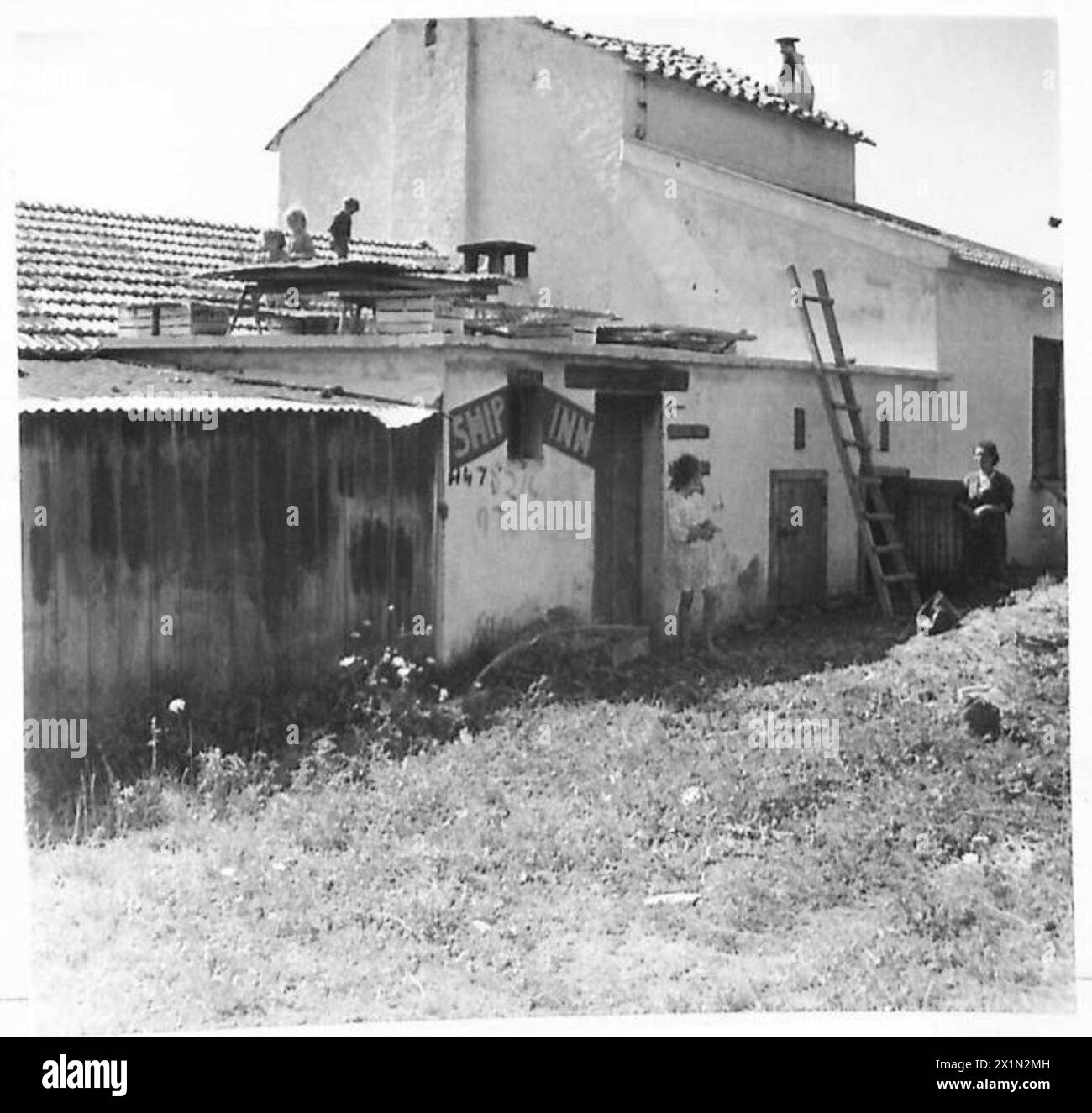 Italienische Zivilisten kehren in ein Haus zurück, das als „Schiffsgaststätte“ bezeichnet wurde, das zuvor von alliierten Landungskräften in Salerno, Italien, besetzt war. Stockfoto
