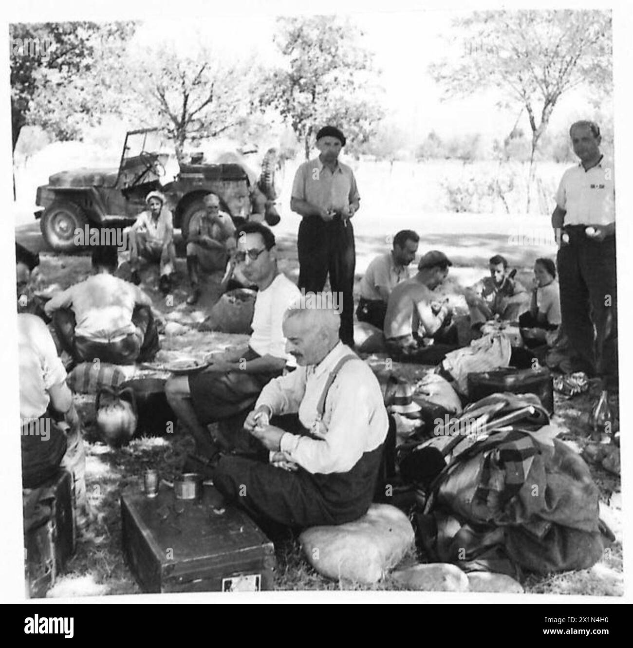 Freigelassene Internierte aus alliierten Armeen essen ihre erste Mahlzeit im Schatten eines Baumes auf Korsika unter Aufsicht der britischen Armee. Stockfoto