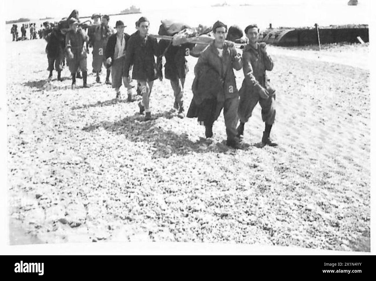 Gefangene, die während der Landung in der Bucht von Salerno gefangen genommen wurden, tragen ihre eigenen Verwundeten unter Aufsicht während der Operationen der Fünften Armee bei der Invasion der Alliierten in Italien zum Strand. Stockfoto