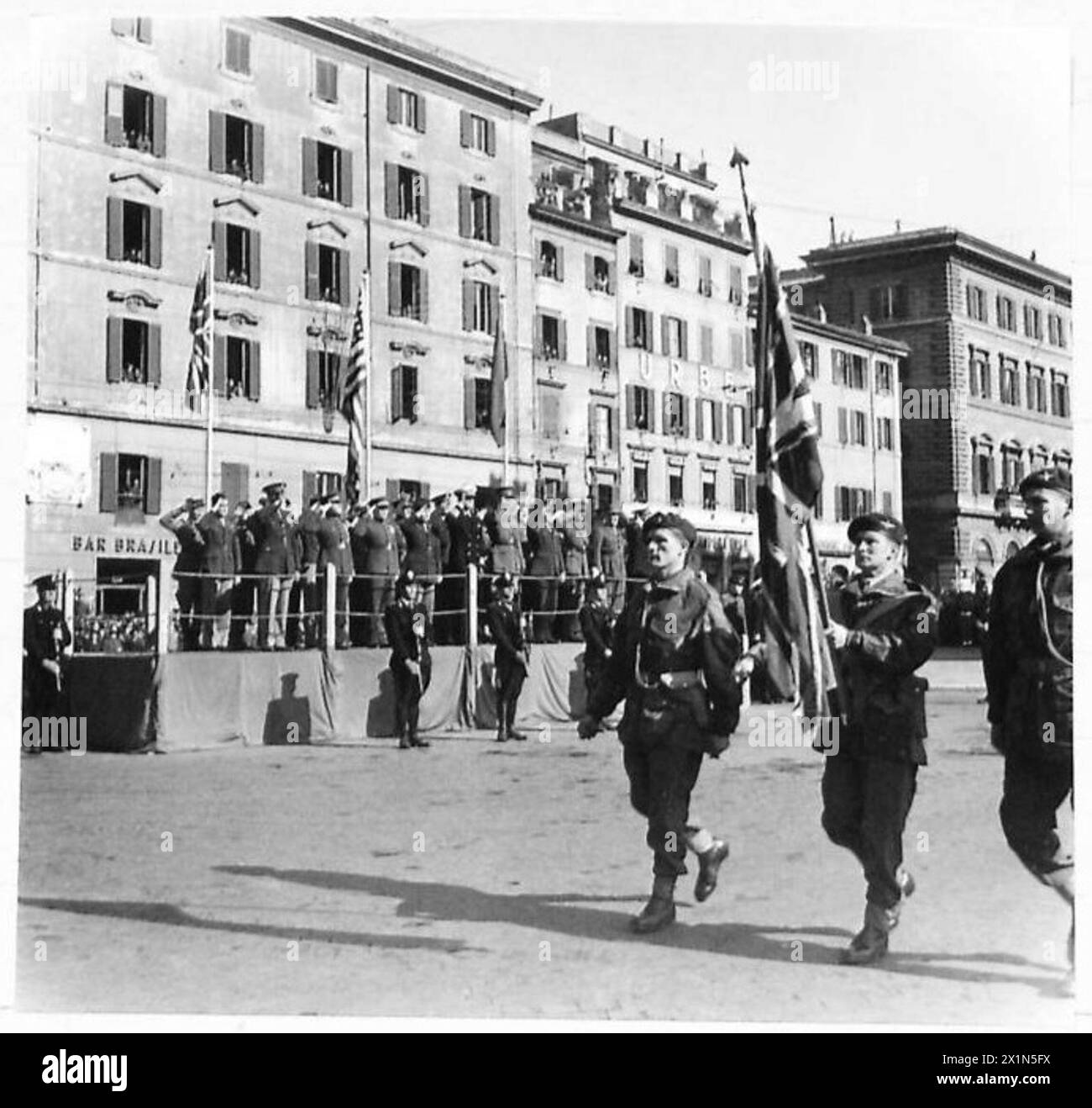 Während der Parade zum Roten Armeetag in Rom grüßen hochrangige britische Armeeoffiziere, während die britische Flagge an der Basis vorbeifährt. Stockfoto