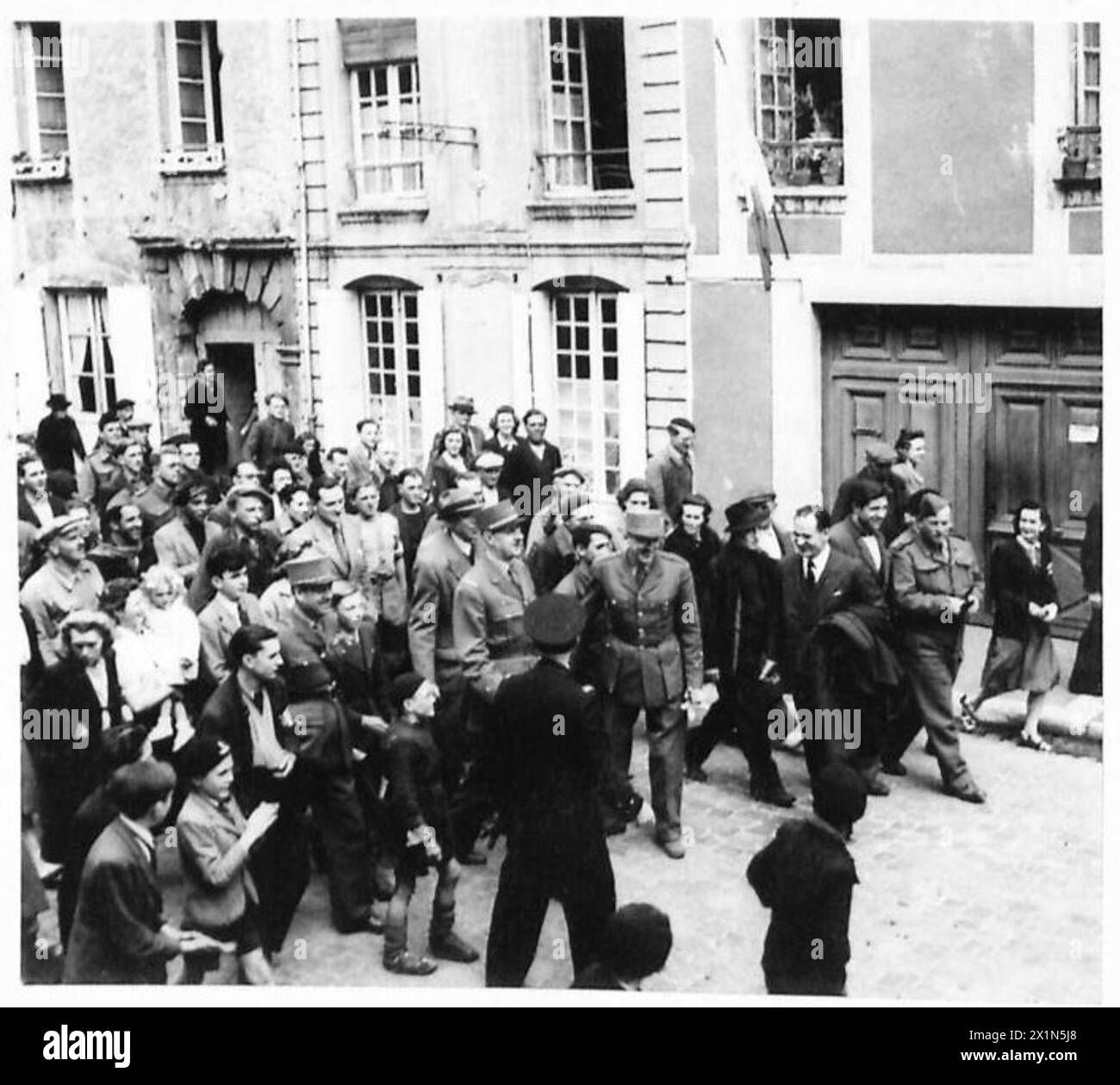 General Charles de Gaulle spaziert durch die Straßen von Bayeux, Frankreich, gefolgt von einer Menge französischer Bürger, unter der Beobachtung der britischen Armee, 21. Armeegruppe. Stockfoto