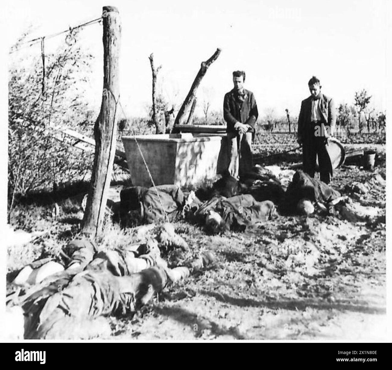 Leichen ermordeter italienischer Zivilisten werden neben einem Brunnen in einem Gebiet der Achten Armee in Italien, der britischen Armee, gezeigt. Stockfoto