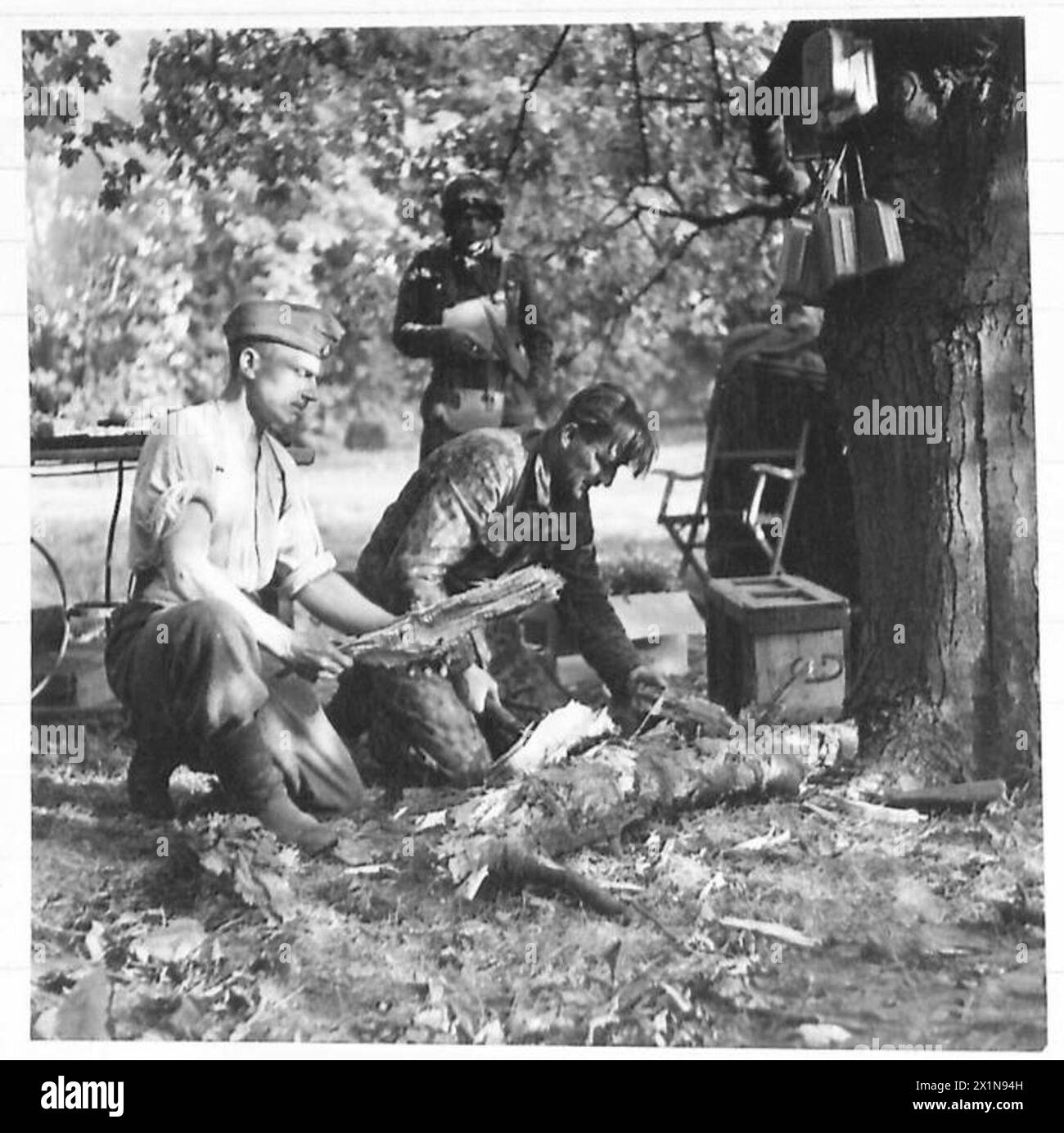 OPERATION 'MARKTGARTEN' - SCHLACHT UM ARNHEIM, SEPTEMBER 1944 - zwei deutsche Gefangene sammeln unter Bewachung Holz. Rechts ist einer der wenigen Gefangenen in seinem mehrfarbigen Anzug. Stockfoto