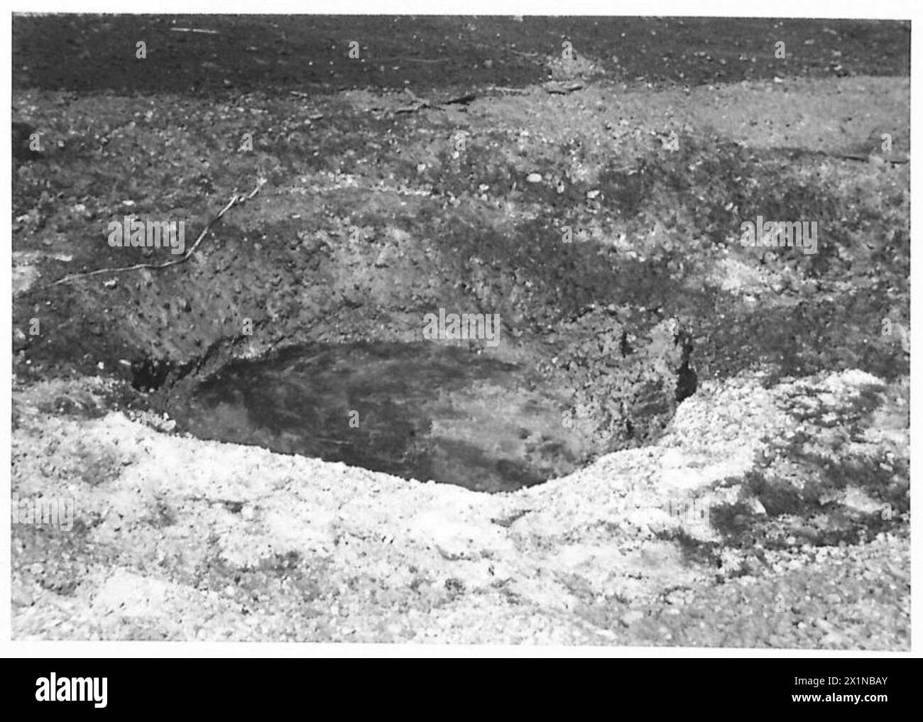 Ein Krater, der durch eine 500-Pfund-Bombe mit 1/10 Sekunden-Nasen-und-Schwanz-Sicherungen erzeugt wurde, beobachtet von der 79. Panzerdivision während eines Sondereinsatzes der britischen Armee. Stockfoto