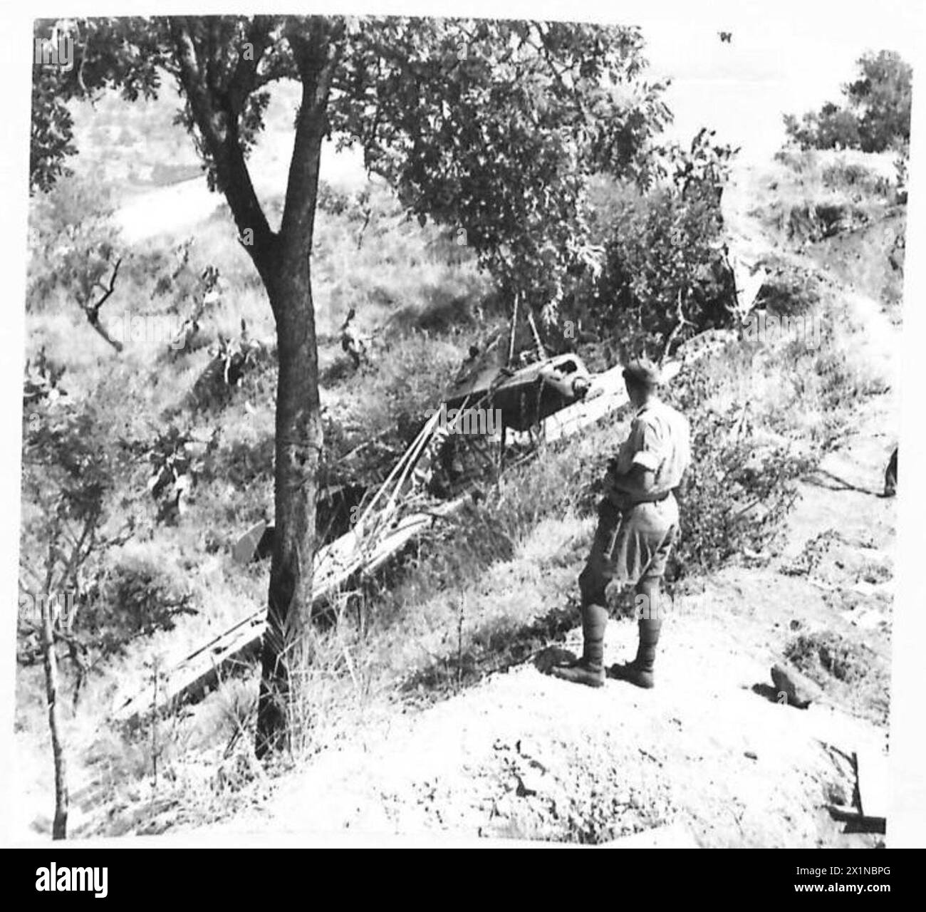 Sergeant E. Male vom 6. Bataillon Green Howards beobachtet ein zerstörtes deutsches Flugzeug auf einem Hügel von Taormina während des Vormarsches der 8. Armee vom Ätna nach Messina. Stockfoto