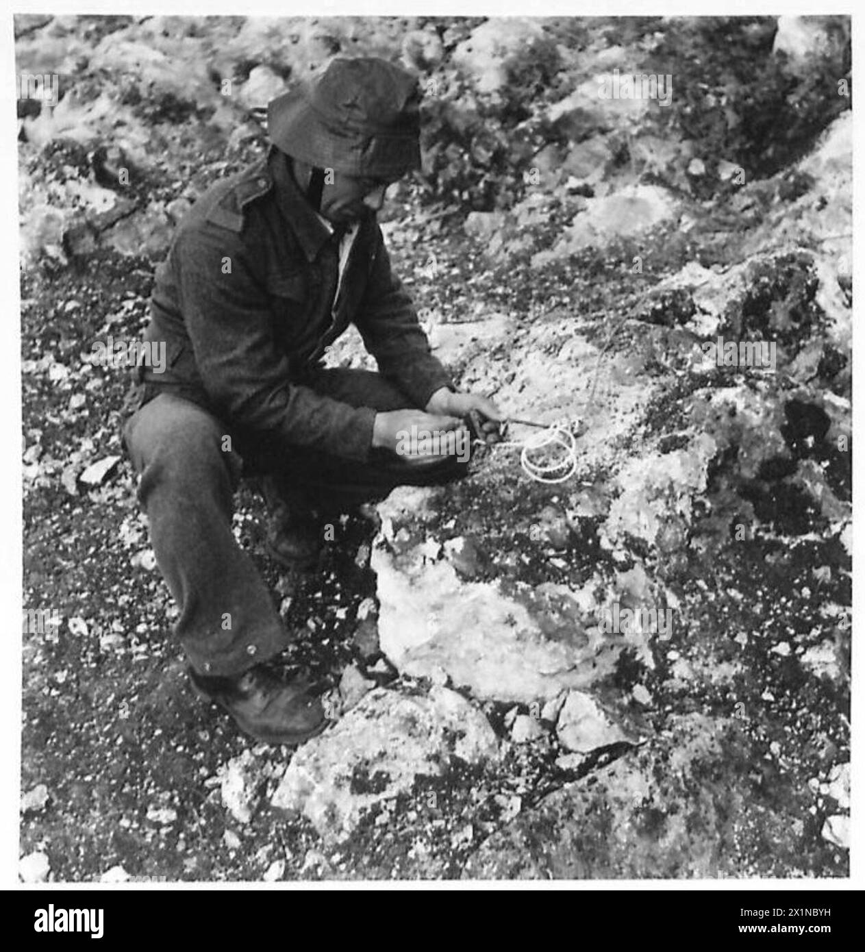 Ein südafrikanischer Bergmann unter Aufsicht der britischen Armee zündet eine Sicherung an einen Sprengstoff an, der während des Baus der Haifa-Tripoli-Eisenbahn entlang der Küste entfernt werden kann. Stockfoto