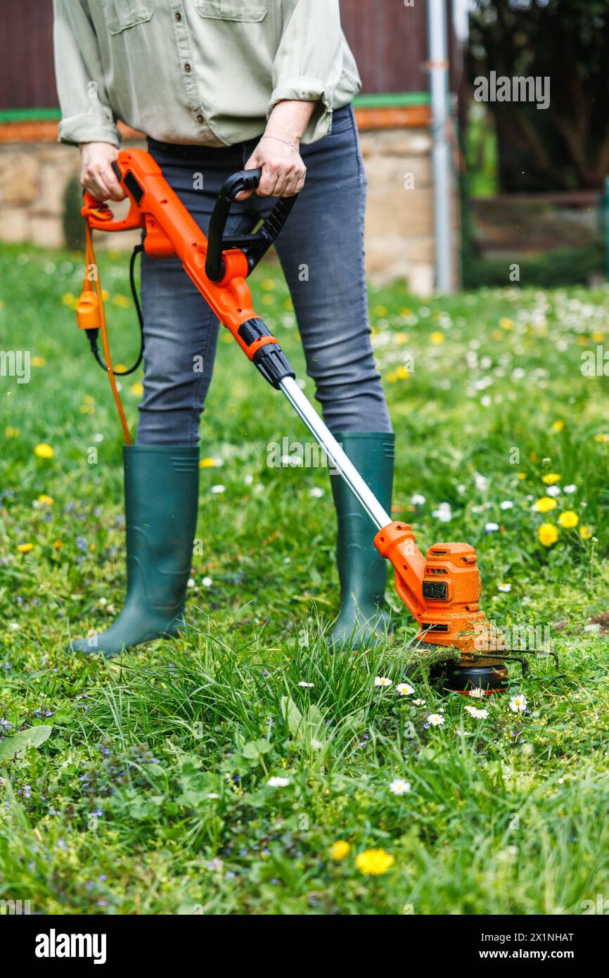 Fadentrimmer. Frau schneidet Gras im Garten. Rasenpflege im Frühjahr Stockfoto