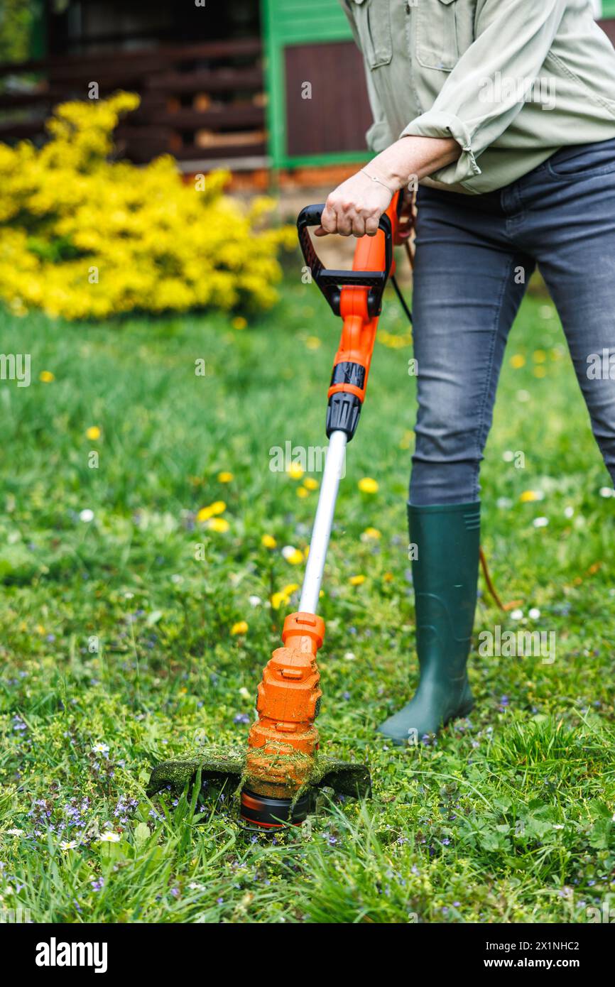 Rasentrimmer. Frau schneidet Gras im Garten. Rasenpflege im Frühjahr Stockfoto