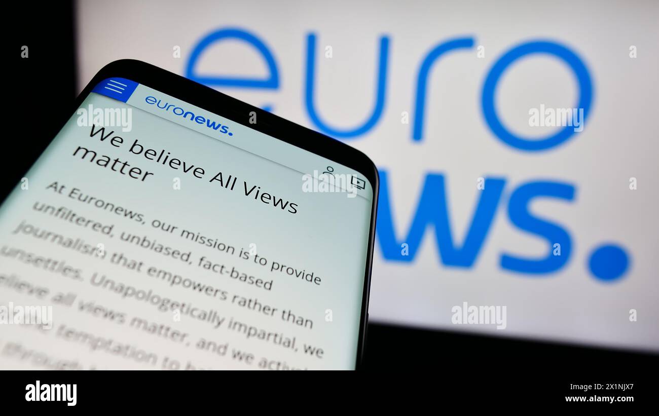 Mobiltelefon mit Website des belgischen Nachrichtenunternehmens Euronews SA vor dem Firmenlogo. Fokussieren Sie sich oben links auf der Telefonanzeige. Stockfoto