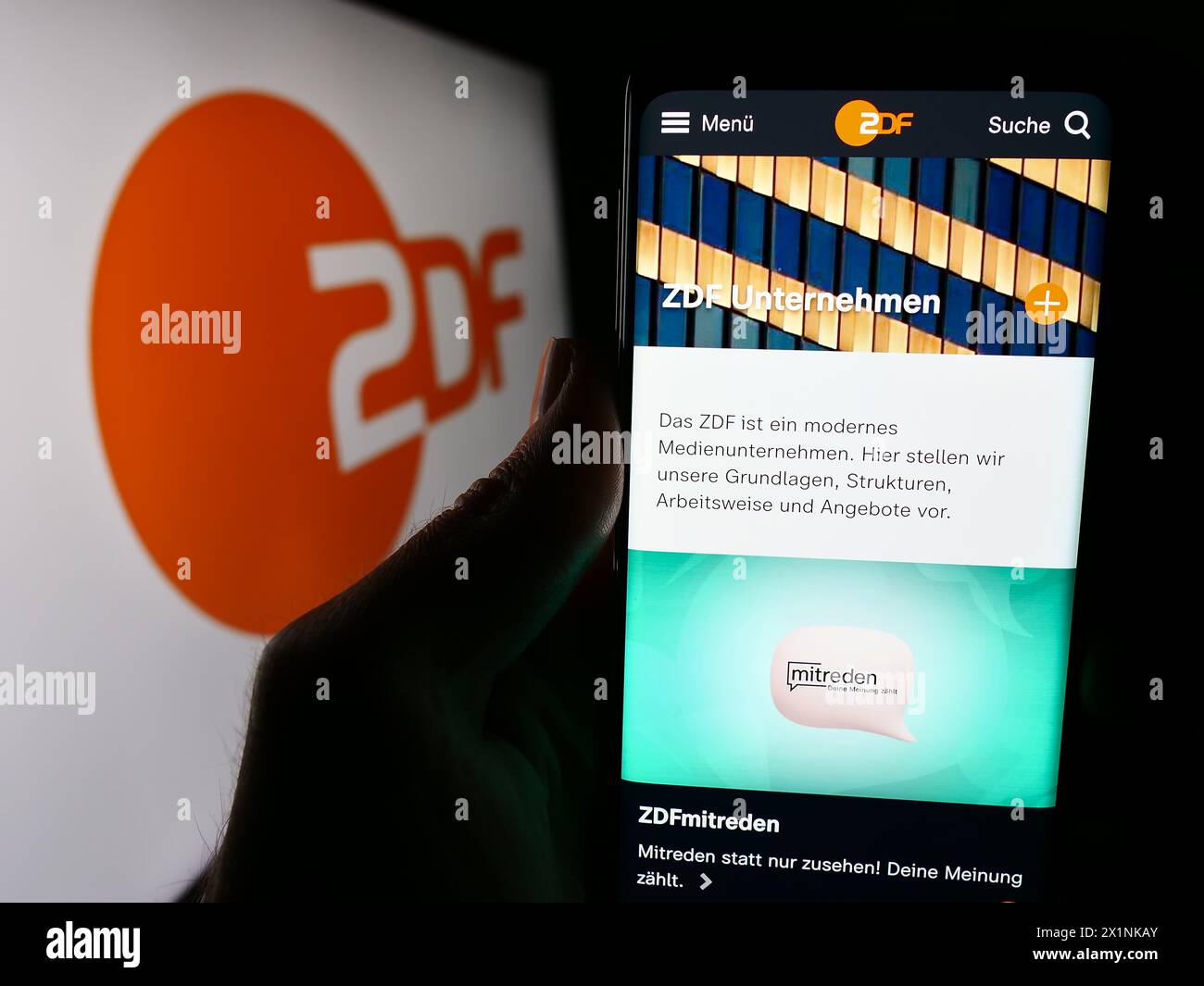 Person mit Smartphone mit Webseite des zweiten Deutschen Fernsehens (ZDF) mit Logo. Konzentrieren Sie sich auf die Mitte des Telefondisplays. Stockfoto