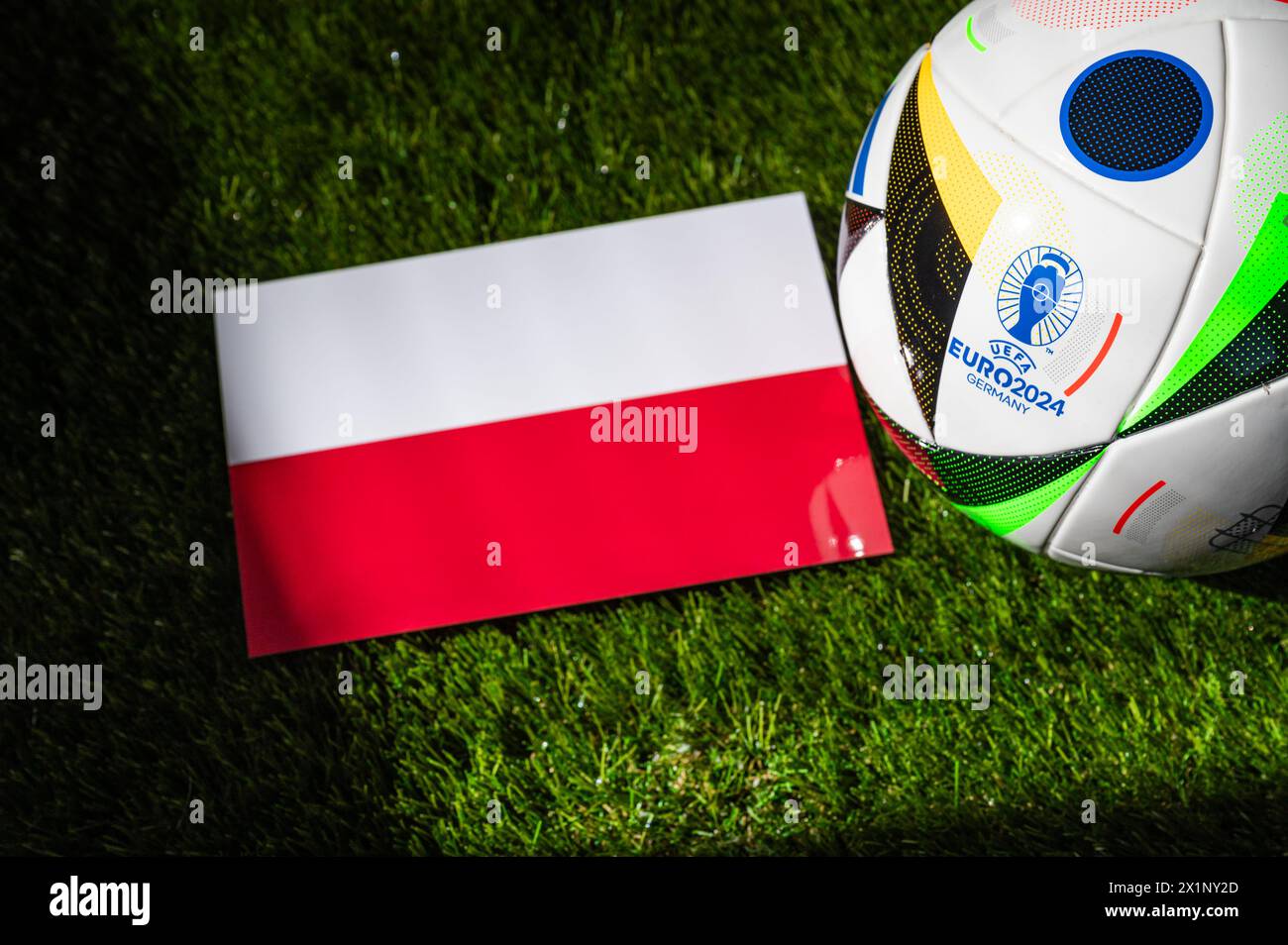 MÜNCHEN, DEUTSCHLAND, 17. APRIL 2024: Polnische Nationalflagge und offizieller Fußball des Fußballturniers Euro 2024 in Deutschland auf grünem Gras platziert. Blac Stockfoto