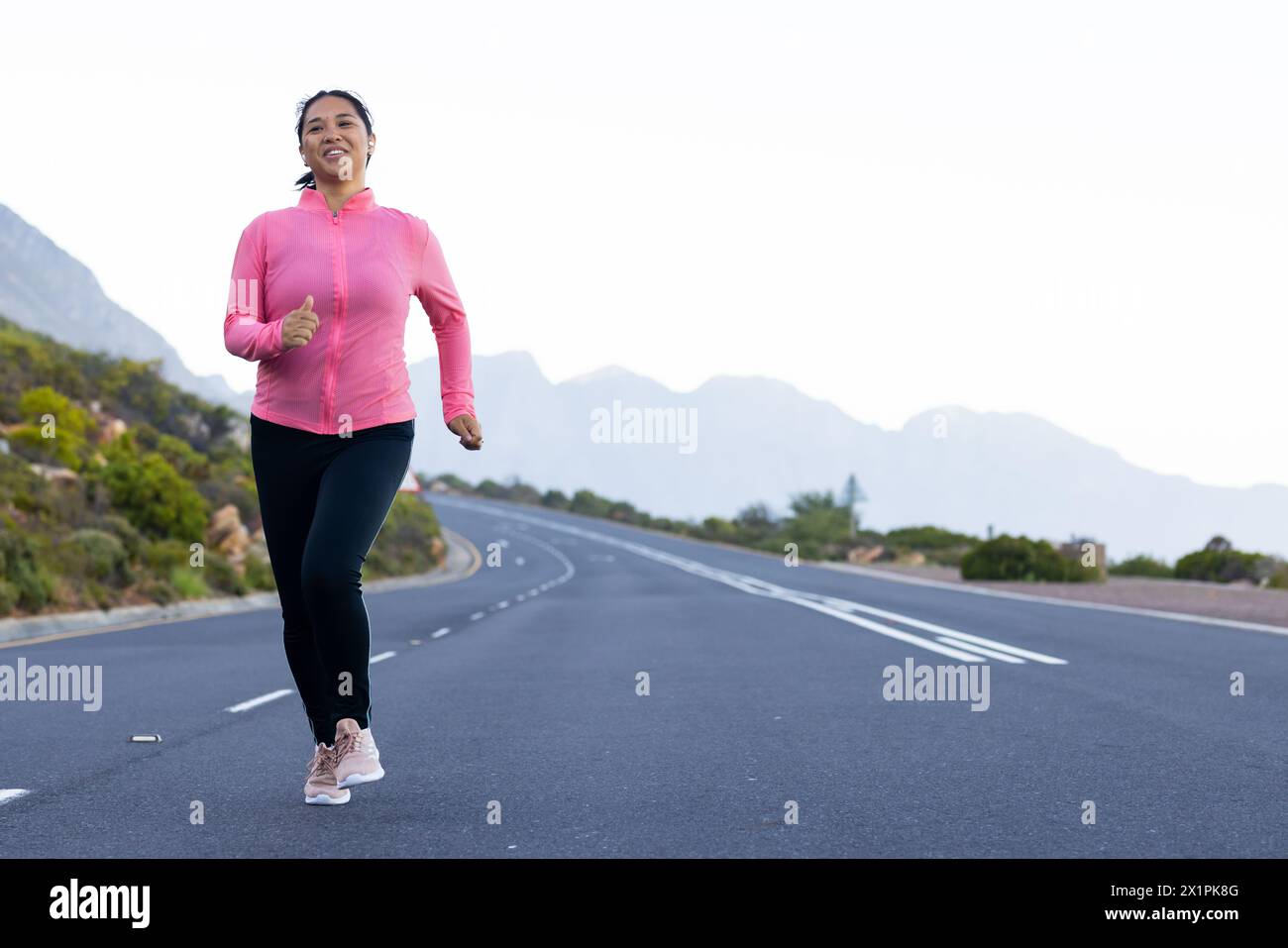 Birassische Wandererinnen joggen auf der Straße mit Bergen und ruhiger Natur im Hintergrund, Kopierraum Stockfoto