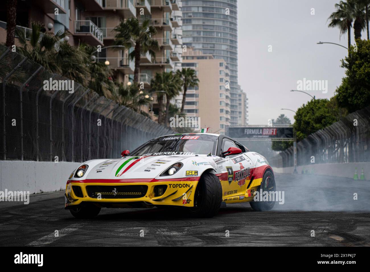 Federico Sceriffo, Fahrer des einsamen Ferrari, wärmt seine Reifen, bevor er am ersten Tag trainieren kann. Formula Drift ist zurück für ein weiteres Jahr des Wettbewerbs und beginnt ihre erste Runde in den Straßen von Long Beach. Mit den in diesem Jahr neu eingeführten Sitzhalterungen konnten sich die Fahrer den Weg an die Spitze kämpfen, anstatt die einzelnen Qualifikationsrunden in den Jahren zuvor. Dadurch konnten die Fans die Veranstaltung besser sehen und die Fahrer ihre Fähigkeiten unter harten Wettbewerbern testen. Nach einem kalten und nassen Wochenende voller Schwierigkeiten, einschließlich eines verheerenden Maschinenbrandes, Stockfoto