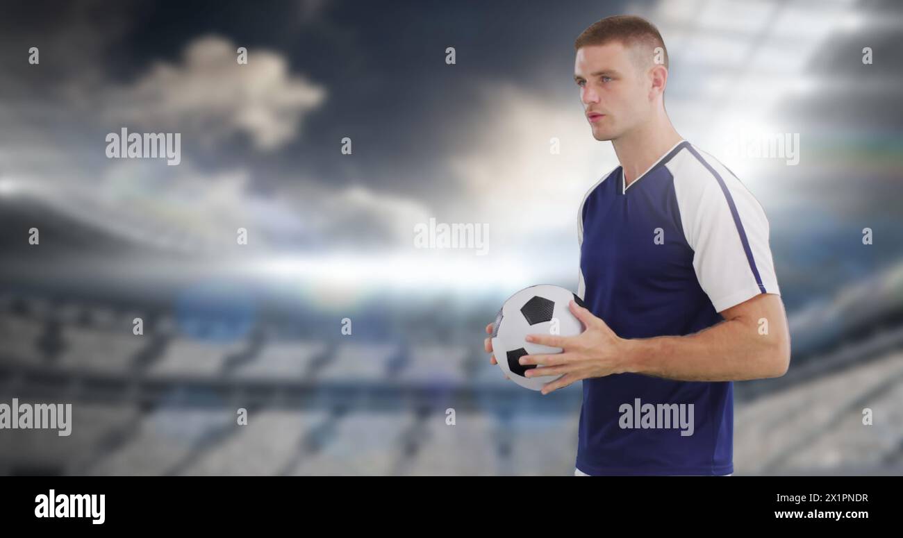 Mann, der Fußball hält, steht im Stadion Stockfoto