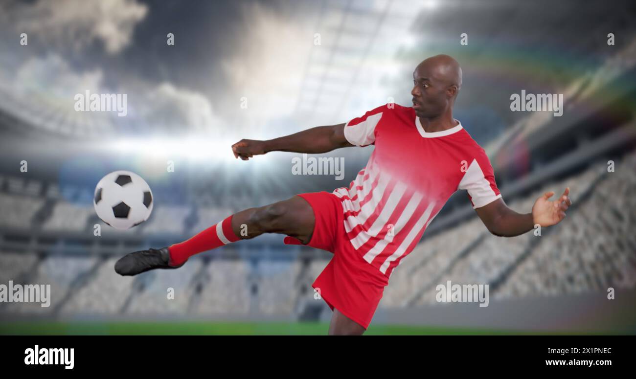 Mann in rot-weißer Fußballuniform, der Ball tritt, Stadion im Hintergrund Stockfoto