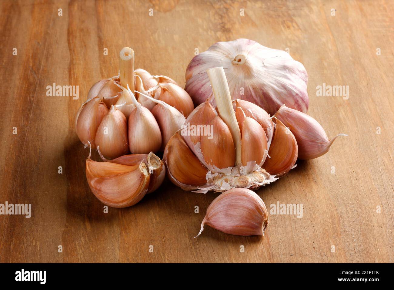 Nahaufnahme rohe, frische Knoblauchzehen und -Zwiebeln auf rustikalem Holztisch. Vorderansicht Stockfoto