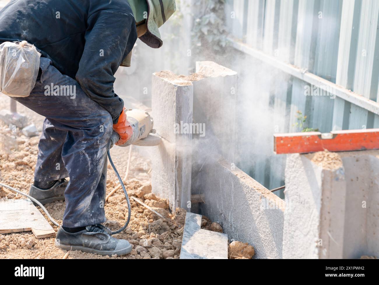 Arbeiter, der Betonpfahlsäule mit einer elektrischen Schneidemaschine schneidet. Arbeiter mit Hochscherschleifer schneiden und fräsen Zement Stockfoto