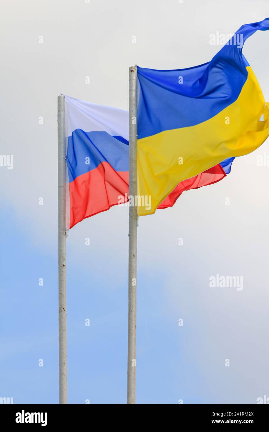 Russische und ukrainische Fahnen winken mit Wind über blauem Himmel. Flachwinkelansicht. Konflikt- und Konfliktkonzept. Horizontale Komposition mit Kopierraum. Stockfoto