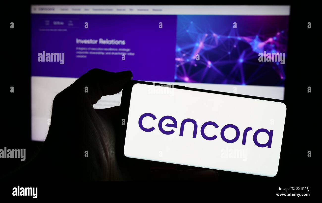 Person mit Smartphone und Logo des US-Arzneimittelgroßhandelsunternehmens Cencora Inc. Vor der Website. Schwerpunkt auf dem Display des Telefons. Stockfoto