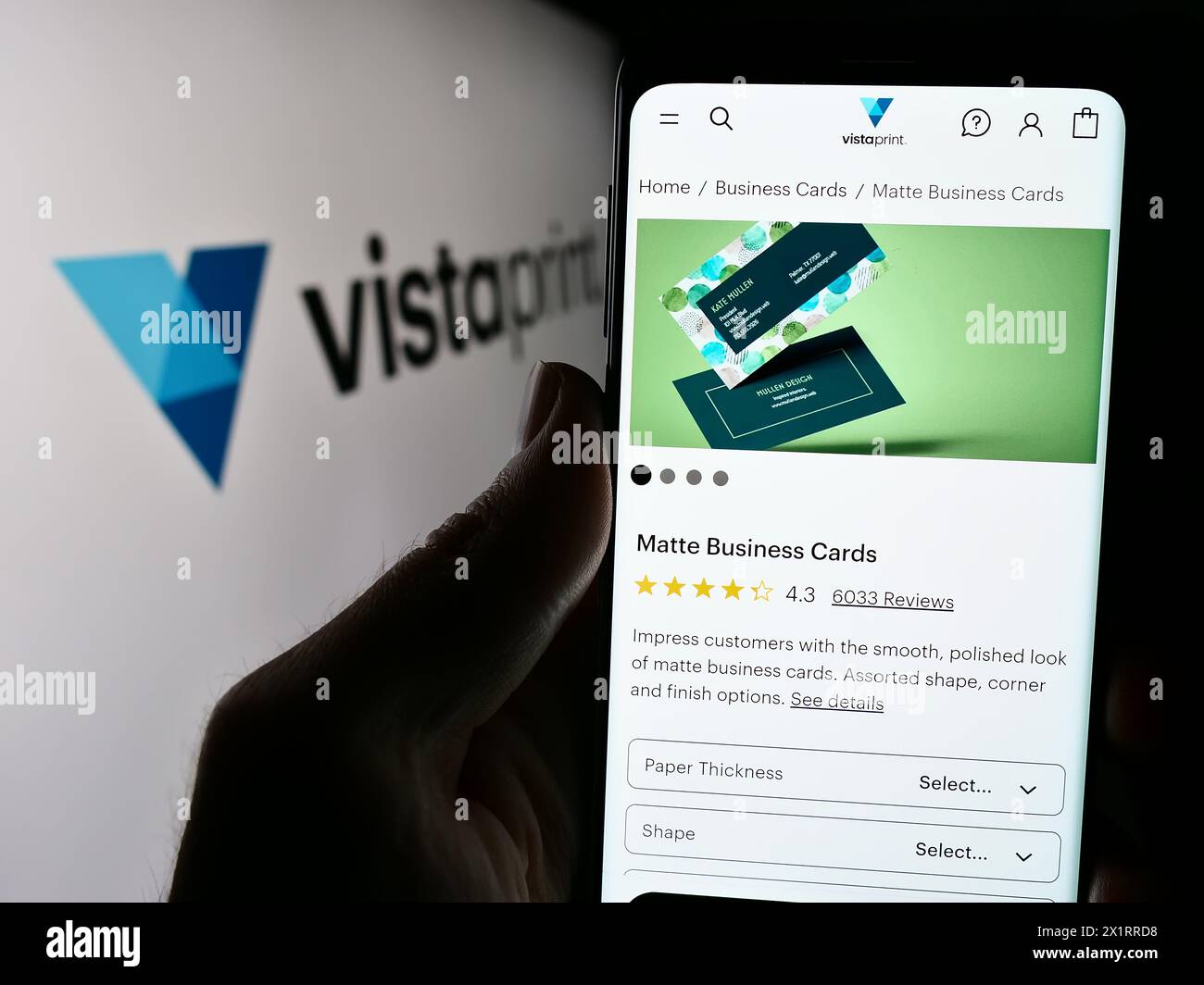 Person, die ein Mobiltelefon hält, mit der Webseite des Unternehmens Vistaprint (Vista) vor dem Logo. Konzentrieren Sie sich auf die Mitte des Telefondisplays. Stockfoto