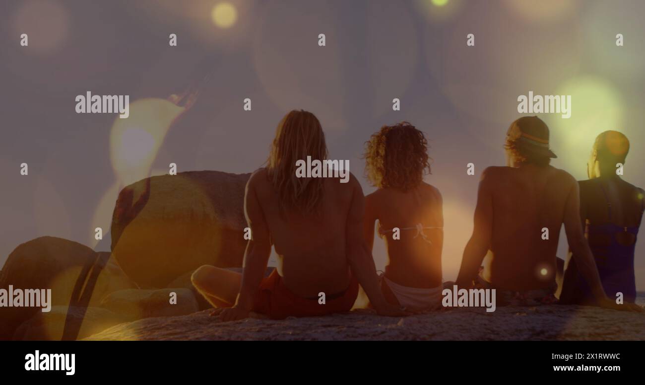 Gruppe von Freunden, die zusammen sitzen und den Sonnenuntergang beobachten Stockfoto