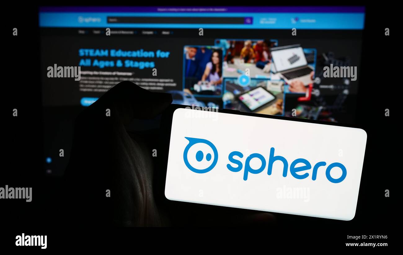 Person, die ein Mobiltelefon mit dem Logo des amerikanischen Unternehmens für Bildungstechnologie Sphero Inc. Vor der Webseite hält. Schwerpunkt auf dem Display des Telefons. Stockfoto