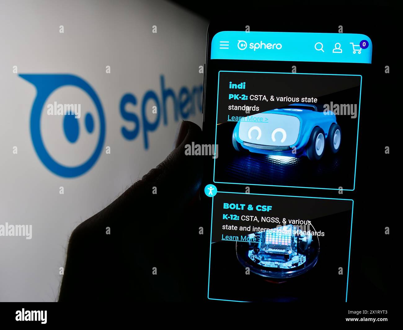 Person mit Smartphone und Webseite des US-amerikanischen Unternehmens für Bildungstechnologie Sphero Inc. Vor dem Logo. Konzentrieren Sie sich auf die Mitte des Telefondisplays. Stockfoto