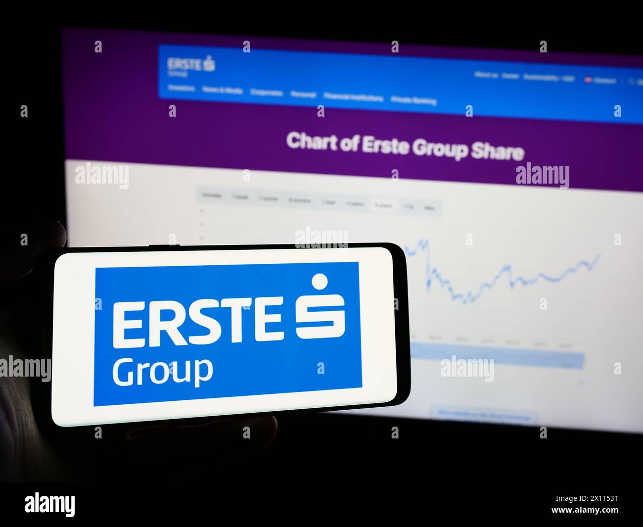 Person mit Mobiltelefon mit Logo des österreichischen Finanzdienstleistungsunternehmens erste Group Bank AG vor der Webseite. Schwerpunkt auf dem Display des Telefons. Stockfoto