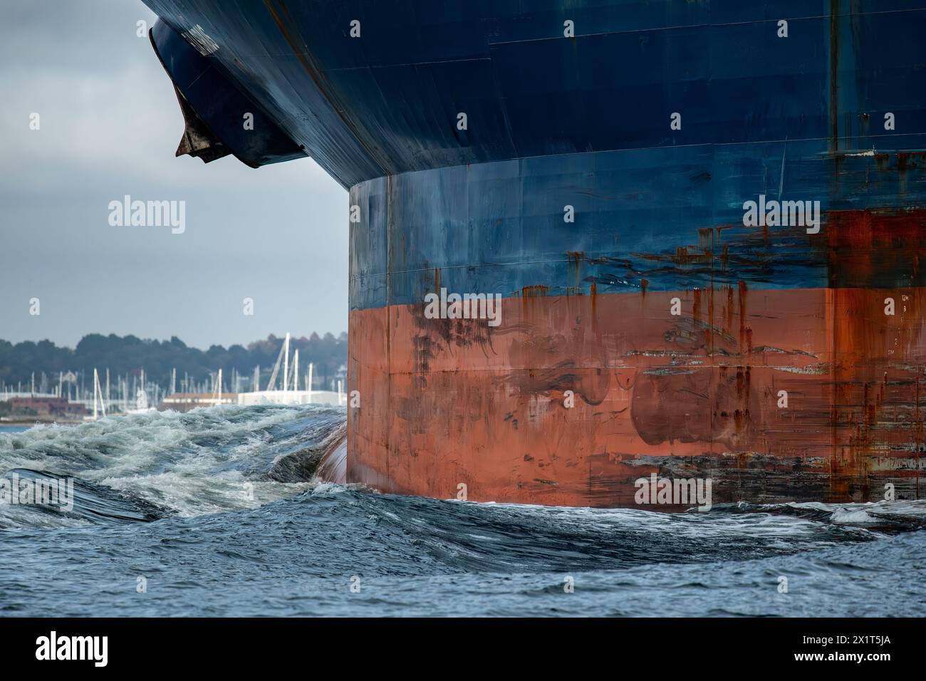 Große blaue Containerschiffe Bug mit rostigen Ankern schiebt eine riesige Bogenwelle durch den Ozean. Stockfoto