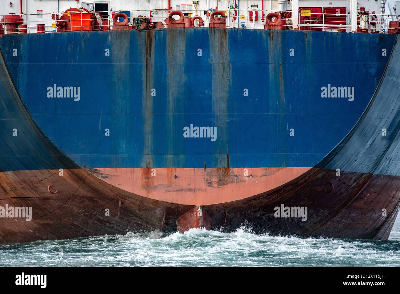 Große blaue Containerschiffe mit Ruder schieben eine riesige Welle durch den Ozean. Stockfoto