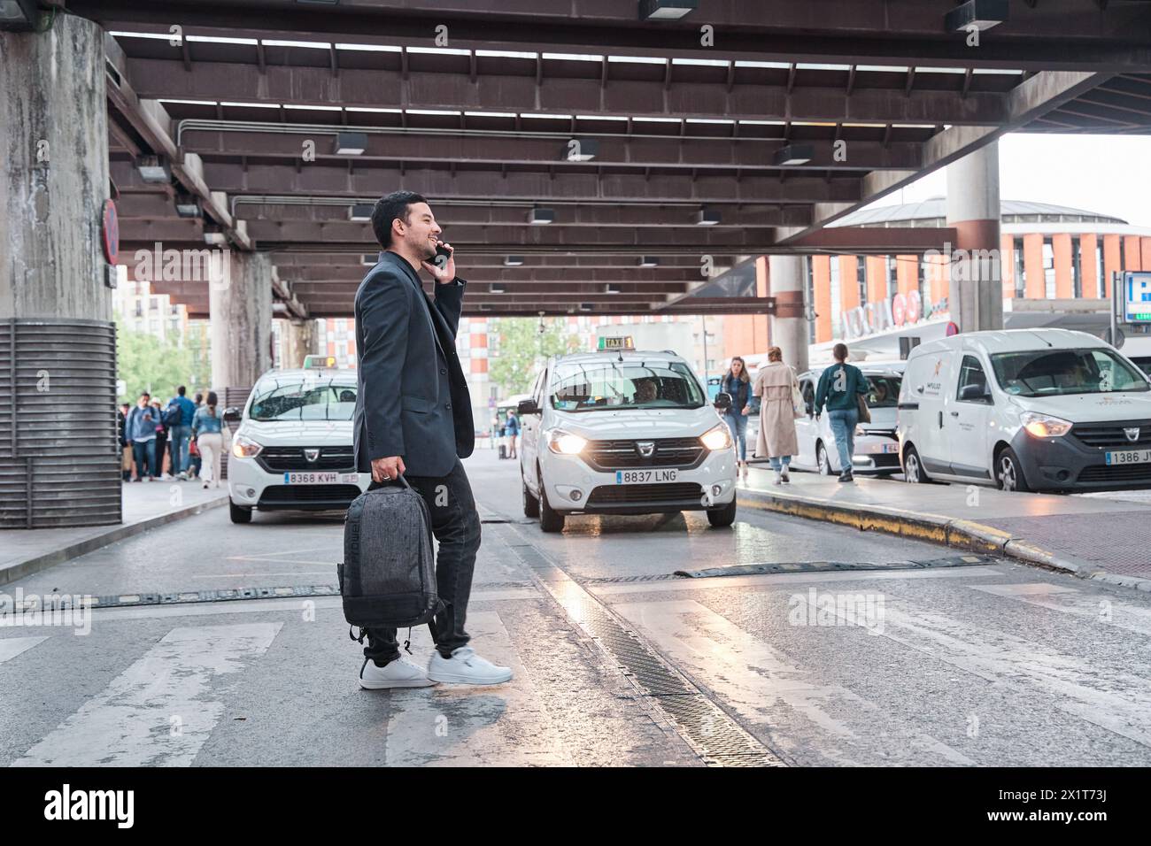 Seitenansicht eines nachdenklichen jungen Geschäftsmannes im Smart-Anzug, der auf dem Handy über das Zebra im Zentrum der Metropole spricht. Stockfoto