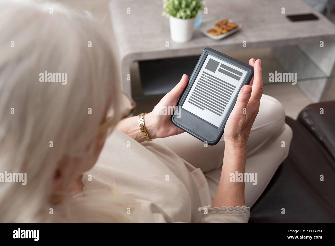 Frau, die auf dem Sofa sitzt und ein E-Book liest. Digitales Buchlesen Stockfoto