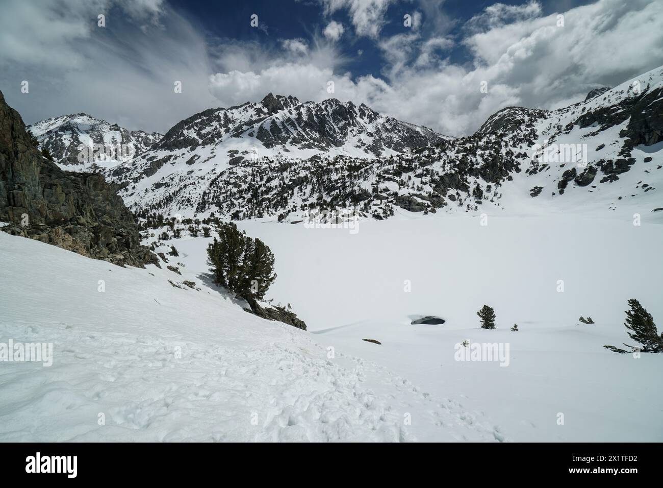 Pacific Crest Trail. Eine schneebedeckte Bergkette mit einem See im Vordergrund. Der Himmel ist klar und blau mit ein paar Wolken Stockfoto