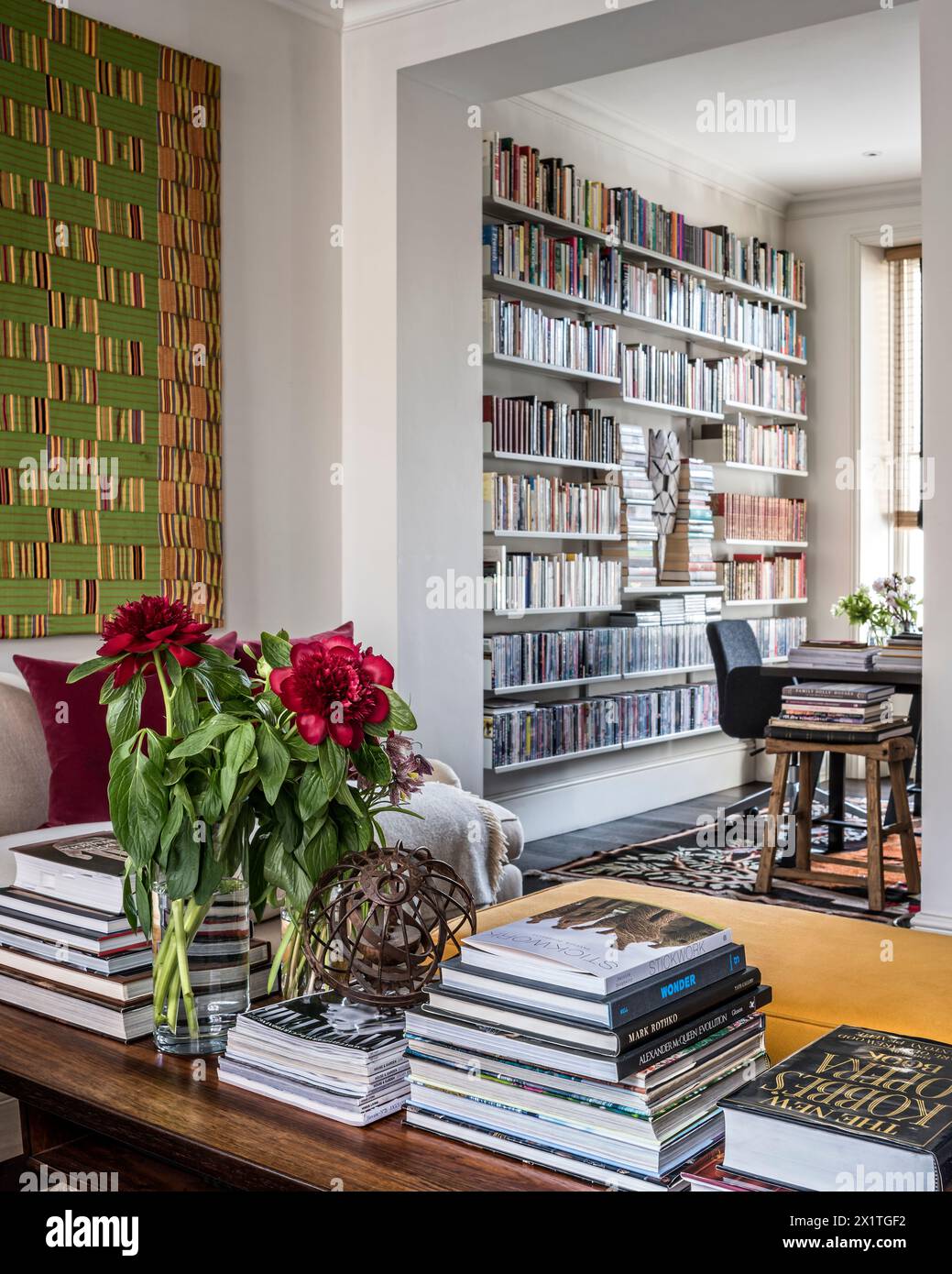 Schneiden Sie Blumen auf einem Couchtisch mit gestapelten Büchern in Chelsea Home, London, Großbritannien Stockfoto
