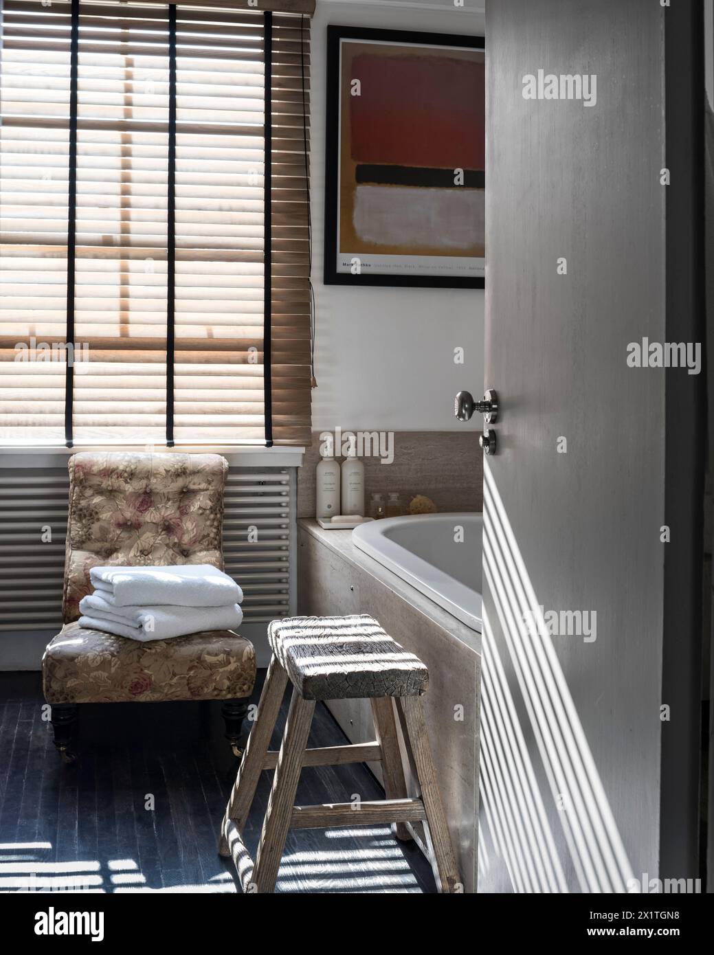 Blick durch die Tür zum Badezimmer mit sonnendurchfluteten venezianischen Jalousien in Chelsea Home, London, Großbritannien Stockfoto