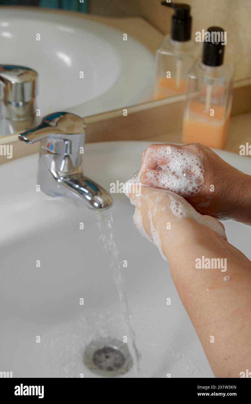 Nahaufnahme einer Frau, die ihre Hände mit Flüssigseife im Waschbecken wäscht. Handhygiene durch Bakterien. Schaumstoffe in Frauenhänden Stockfoto
