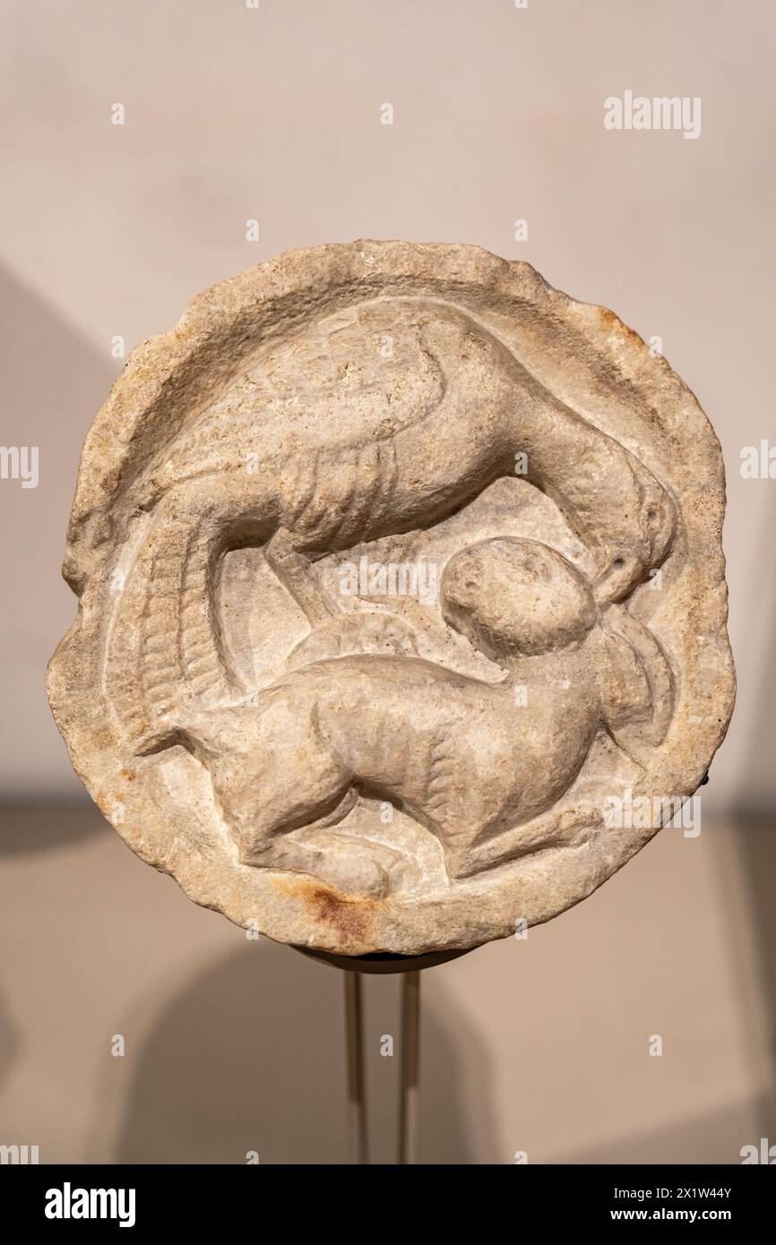 Nahaufnahme von antiken Skulpturen, die in einen runden Marmorstein gemeißelt wurden und einen Raubvogel darstellen, der ein Kaninchen jagt Stockfoto