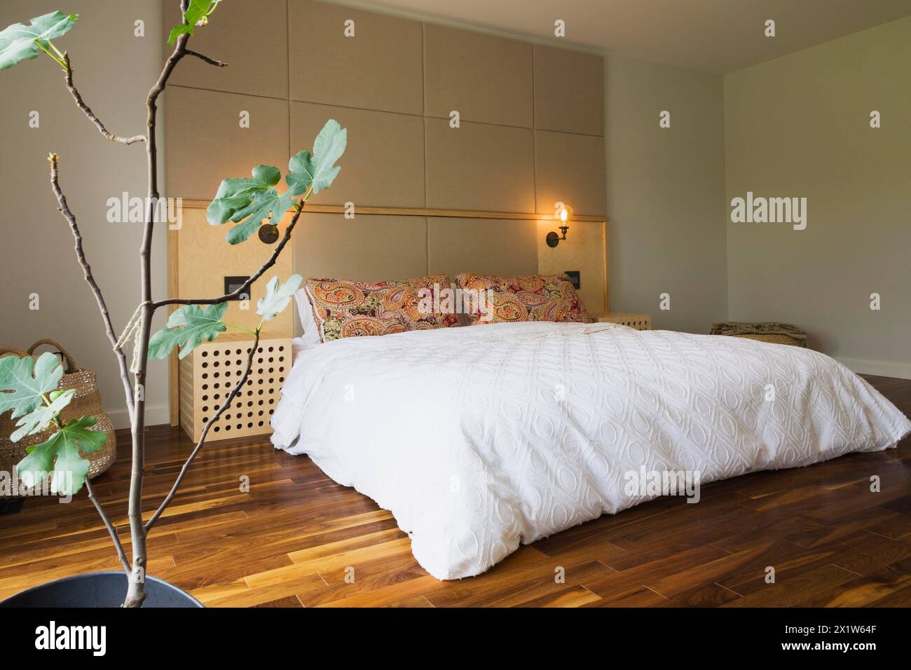 King-Size-Bett mit weißer Bettdecke im Schlafzimmer mit amerikanischem Walnussholzfußboden im Obergeschoss im modernen Cube-Stil Haus, Quebec Stockfoto