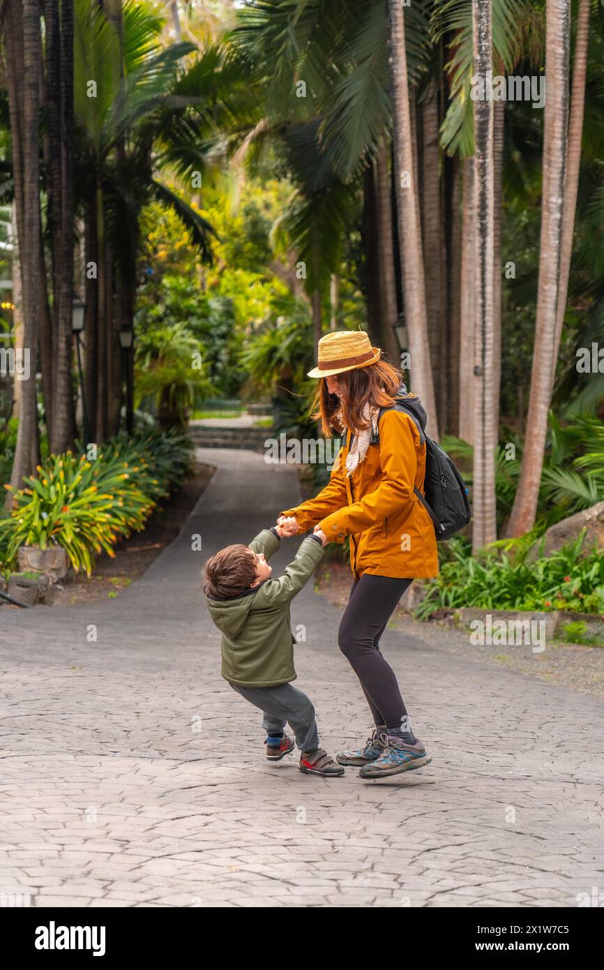 Eine Frau und ein Kind spielen in einem Park. Die Frau hält die Hand des Kindes und beide lächeln Stockfoto