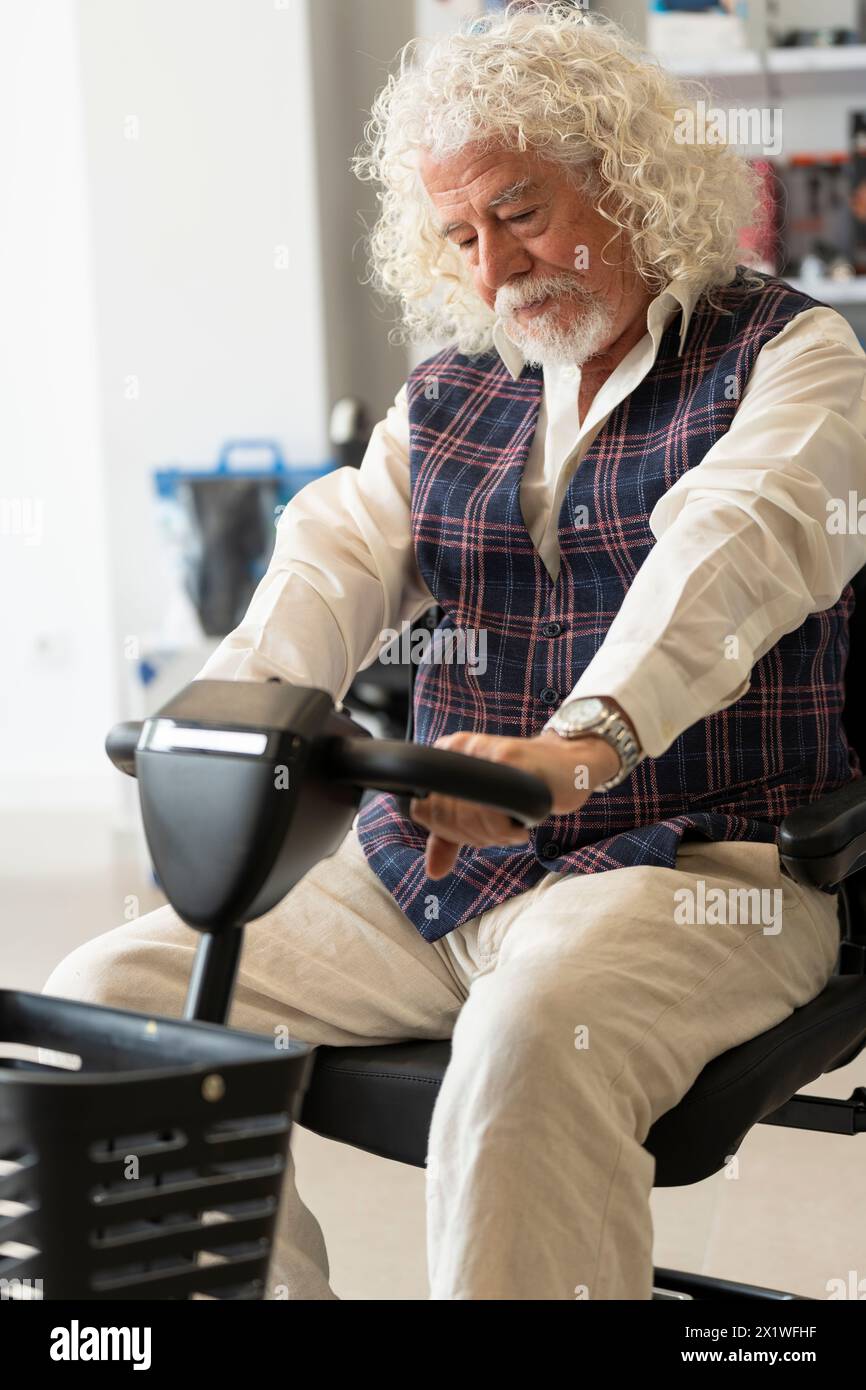 Ein älterer Mann in einem Orthopädieladen, der einen Elektroroller ausprobiert Stockfoto