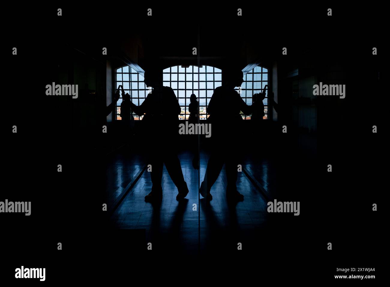 Eine symmetrische Reflexion der Silhouette eines Touristen, der mit seinem Smartphone im Centro Portugues de Fotografia in Porto im Norden fotografiert Stockfoto