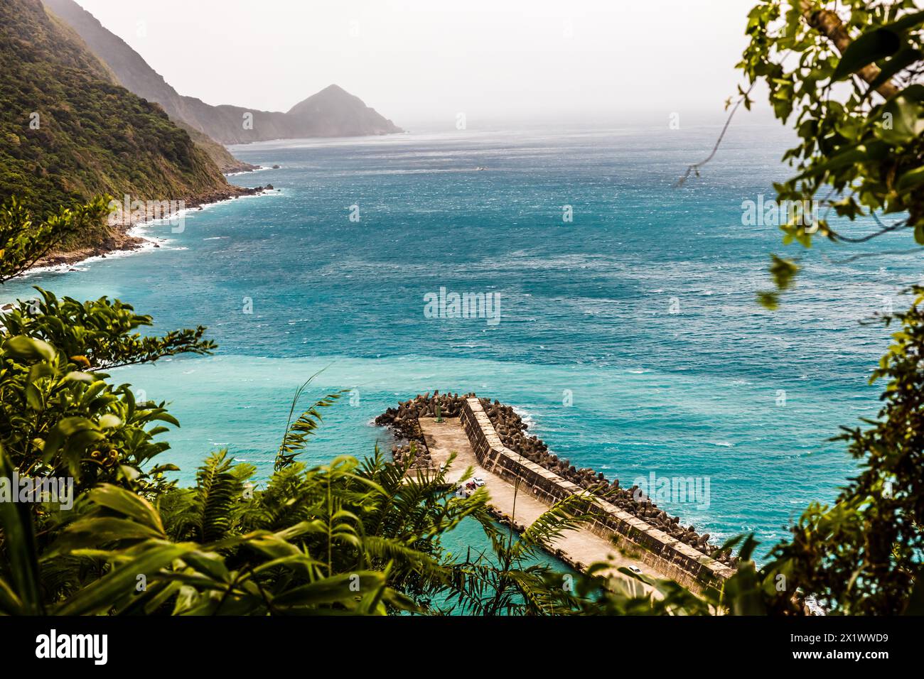 Ein Vogelblick über einen Fischerhafen mit den Farben des blauen Meerwassers von Tiffany und der grünen Berge sorgt für ein frisches und angenehmes Gefühl. Stockfoto