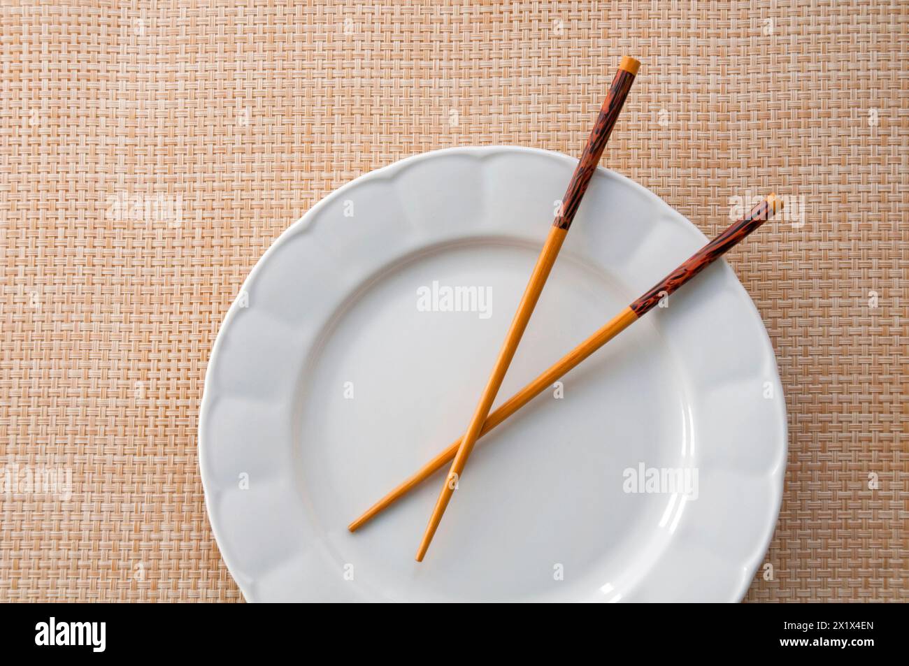 Chinesische Essstäbchen auf leerem Teller. Stockfoto