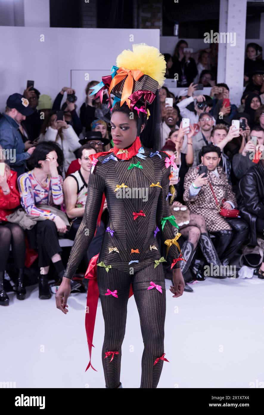PAM Hogg Modenschau während der Londoner Fashion Week schwarzes Model auf einem Laufsteg in schwarzen Einteiler und bunten Schleifen Stockfoto