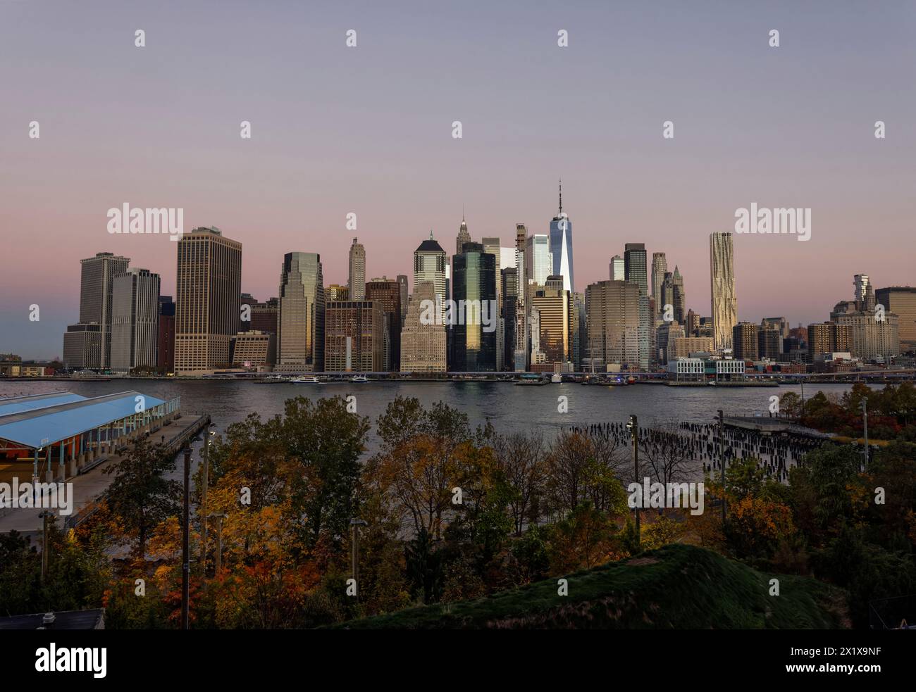 Wolkenkratzer im Finanzviertel Lower Manhattan, die am frühen Morgen New York über den East River vom Old Pier 1 im Brooklyn Bridge Park Greenway aus gesehen werden Stockfoto